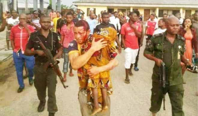 The suspect carrying his son’s corpse in the presence of police and residents