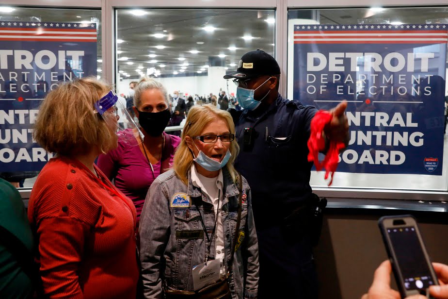 A policeman shows the exit door to a woman who showed up with dozens of other Donald Trump supporters at the TCF Center in Detroit, Mich., In an attempt to stop the counting.