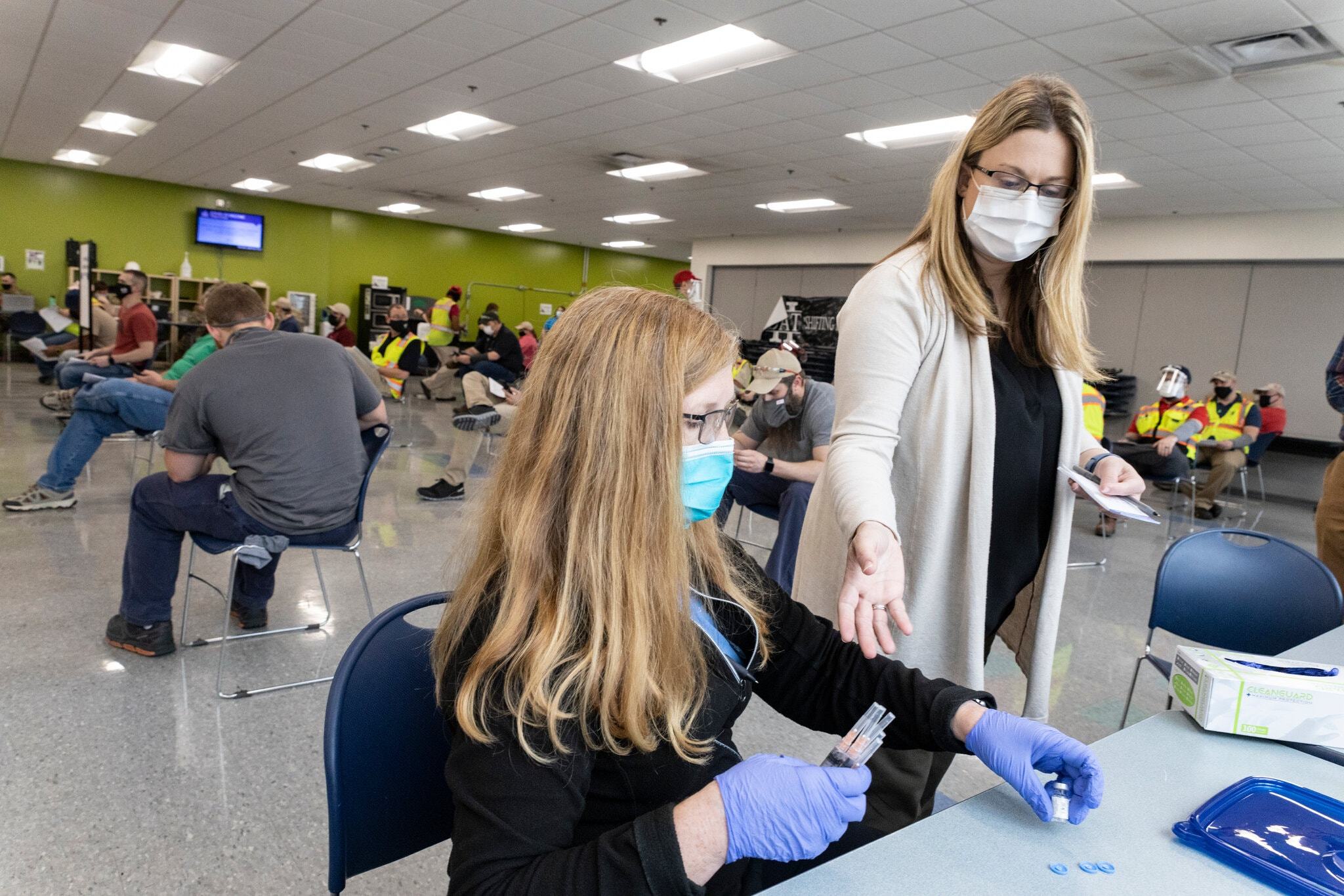Health care workers prepared doses of a Covid-19 vaccine in Buffalo, W.Va., last month. Gov. Jim Justice announced a plan to give savings bonds to young people who get vaccinated.Credit...