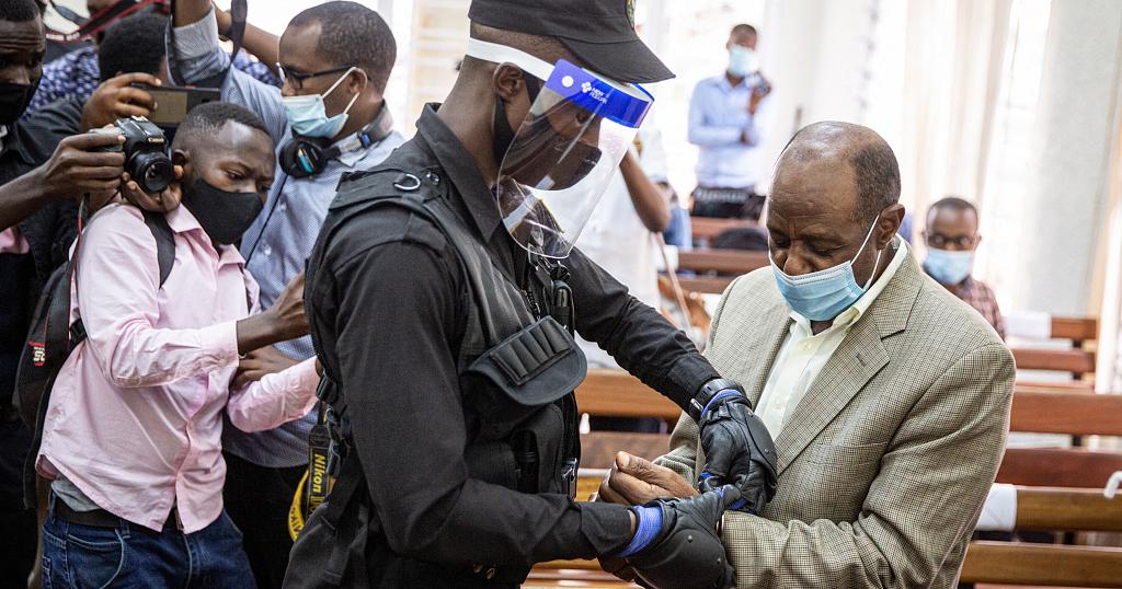 In this file photo taken on September 14, 2020 "Hotel Rwanda" hero Paul Rusesabagina (R) is handcuffed by a police officer after his pre-trial court session in Rwanda