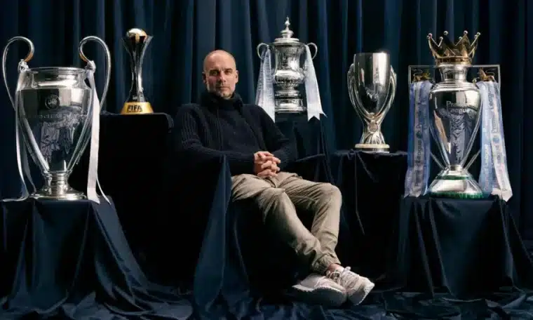 Pep Guardiola poses with some of the major titles he won at Manchester City.