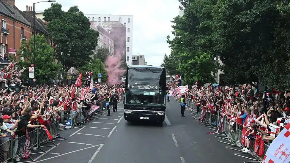 Arsenal bus drives by a crowd of fans as the club celebrate their Premier League triumph.
