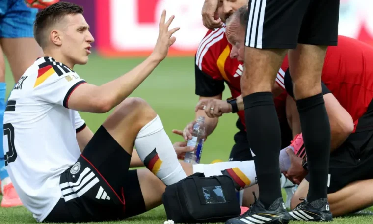Nico Schlotterbeck being attended to by medics during a 2026 FIFA World Cup game.