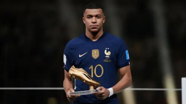 Kylian Mbappe posing with the Golden Boot he won during the 2022 FIFA World Cup.