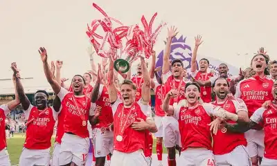 Arsenal players lifting the 2025-2026 Premier League trophy.