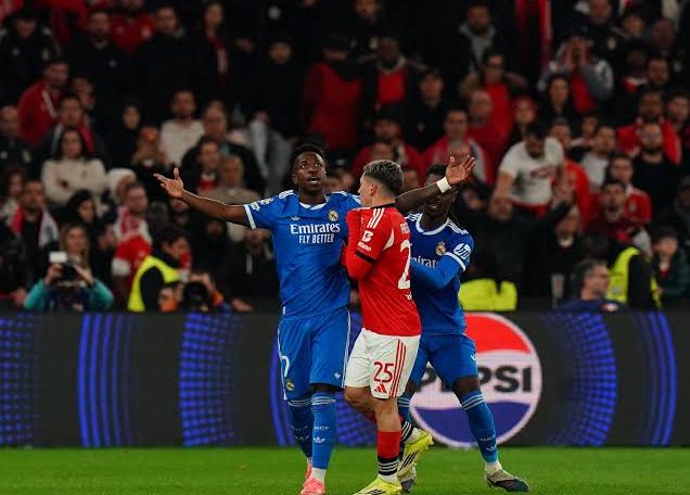 Gianluca Prestianni of Benfica covering his mouth to talk to Vinicius Junior of Real Madrid during a Champions League game.
